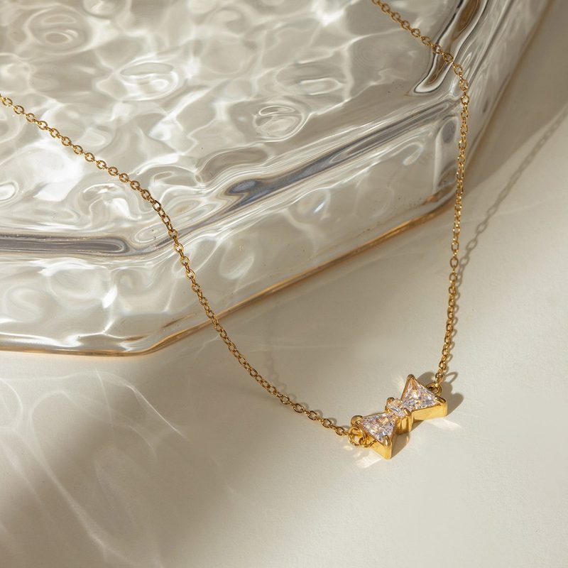 Gold bow pendant necklace with a small stone