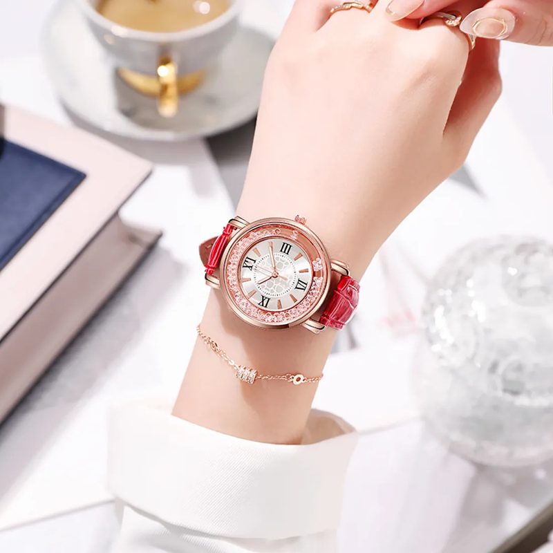 Rose toned watch with a sparkle dial and a red strap on a plain background